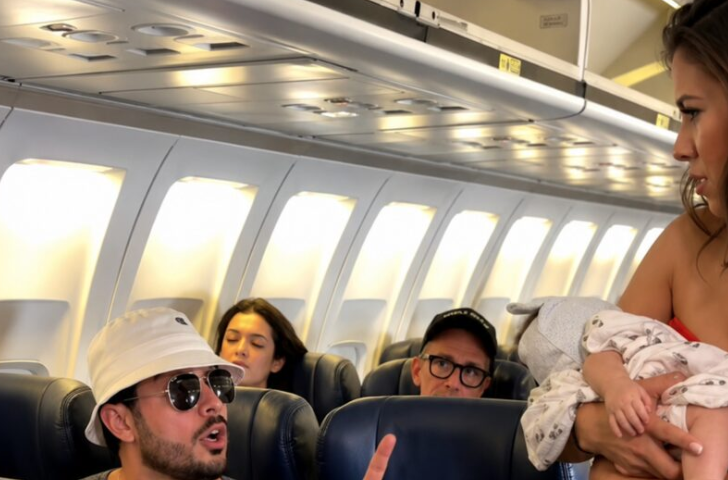 A tall, impeccably dressed elderly man in a bespoke navy suit stood up from First Class, stepping through the velvet curtain into the economy cabin. His presence alone commanded absolute silence. Beside him walked the lead flight attendant, holding a tablet and looking deathly pale.