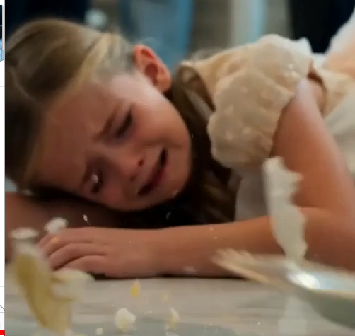 The Grandmother forcefully shoves the Daughter away from the banquet table.