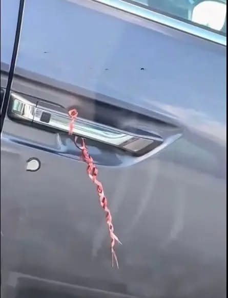 I was shopping at a nearby store, and when I returned to my car, I noticed something strange. There was a string or ribbon attached to the door handle. This has happened to me twice now. What could it mean?