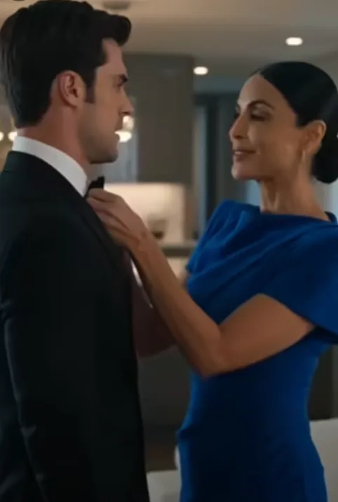 The dimly lit apartment was thick with tension as Elena gently adjusted the bowtie of her husband