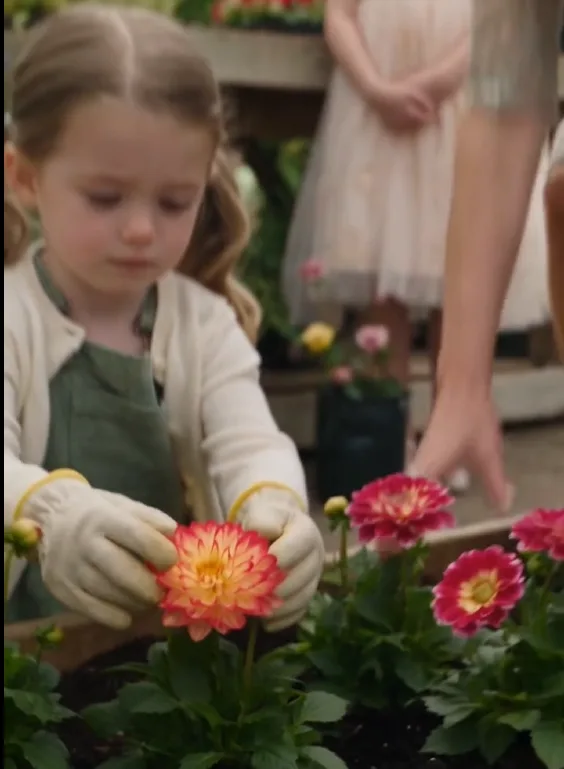 Ruby kneels beside a small flower bed she has carefully planted.