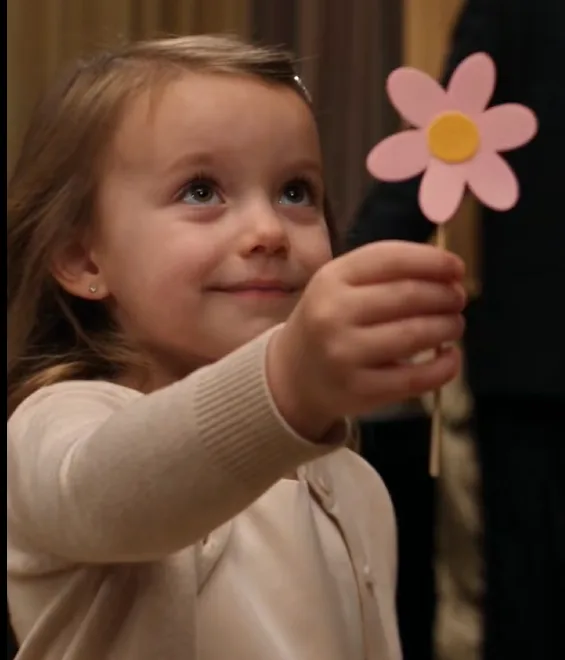 Three-year-old Elsie Lombardi walked across the backstage reception area holding a small paper flower she had made herself.